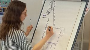 Emily Fellah drawing a llama on a flipchart during a step-by-step character tutorial