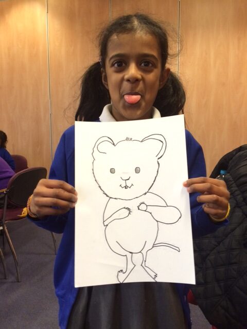 A girl holding up a drawing of a mouse