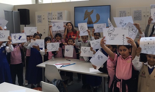 Emily Fellah with a school group holding up the drawings they've created in the workshop
