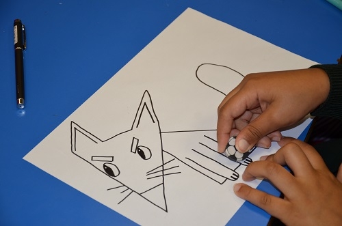 A pupil erasing pencil lines from an inked fox character following a step-by-step tutorial.