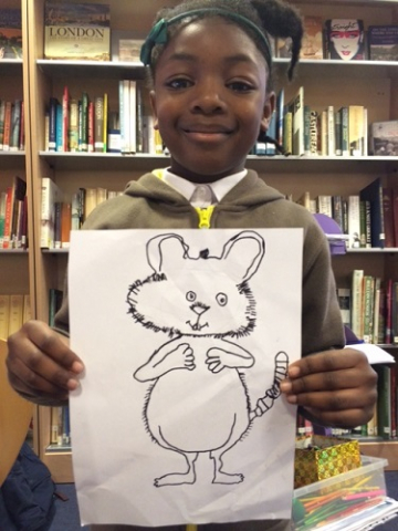 A girl holding up a drawing of a mouse