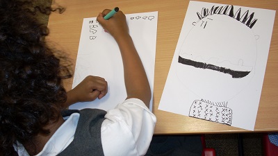 View over the shoulder of a pupil creating character doodles